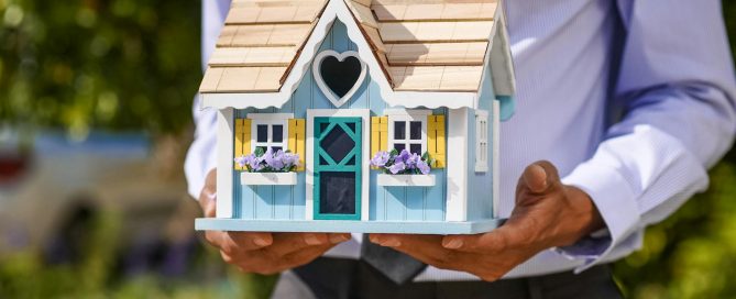 Maqueta de casa sostenida por manos, representando el mercado inmobiliario y el crédito hipotecario en Argentina
