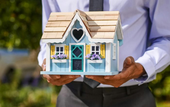 Maqueta de casa sostenida por manos, representando el mercado inmobiliario y el crédito hipotecario en Argentina